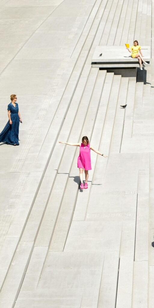 Persone su ampie gradonate in uno spazio pubblico contemporaneo. Significato: diversità di persone che vivono uno spazio pubblico.