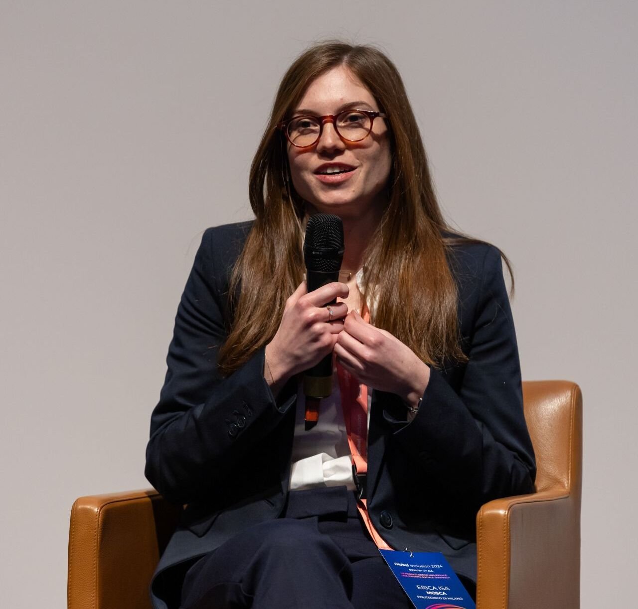 Ritratto di Erica Isa Mosca ad un convegno. Con occhiali e giacca blu.