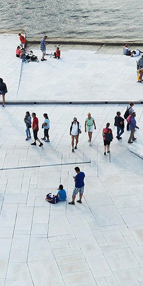 Vista dall’alto di una piazza con diverse persone in movimento o in gruppo.